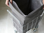 BRIDブリッドのランドリーストレージスクエア45L、銀色のハンドル付き灰色の収納バッグがキャスター付きカートに取り付けられている様子