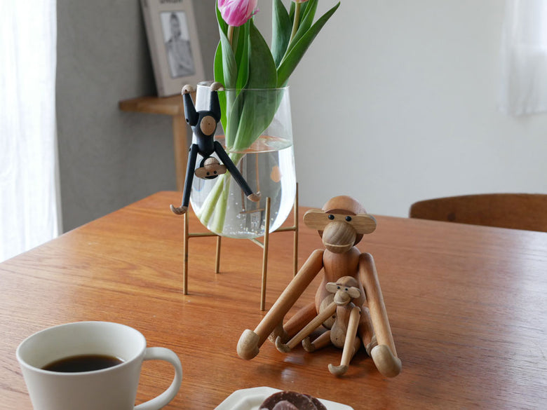 カイ ボイスン製の木製モンキーとカップ、キッチン用品、観葉植物が並ぶ静物写真