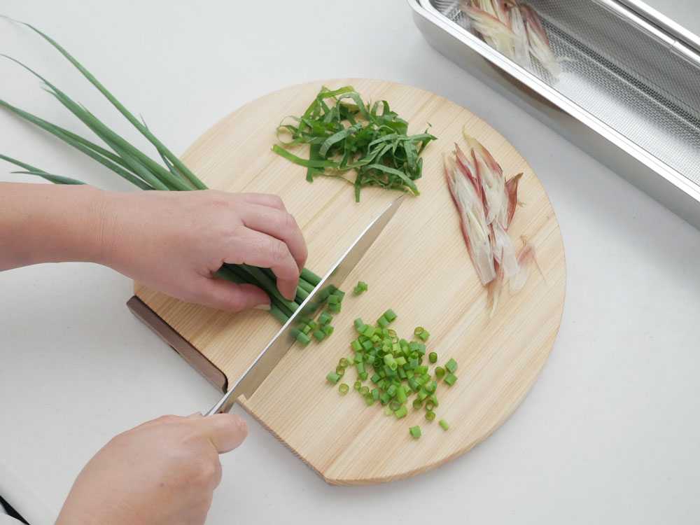 ヒノキ製まな板と野菜、調理器具が並ぶキッチンカウンター