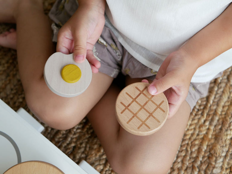 dou?ブランドのままごとがっき pop panセット。ビーチ材、MDF、ゴム製のフライパン、たまご、ハンバーグ、フライ返しなどのおままごとキッチンアイテムが並んでいる画像
