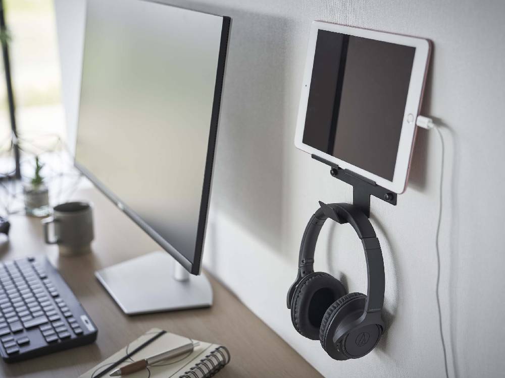 スチール製の【smart/スマート】ウォール スマートフォン＆ヘッドホンホルダーが壁に取り付けられ、スマートフォンとヘッドホンを整理整頓している様子