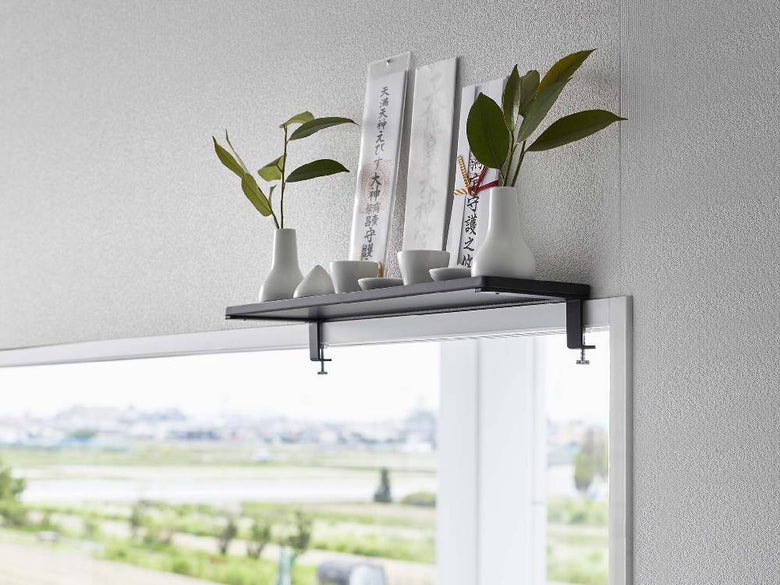 窓際に設置されたtowerブランドのスチール製鴨居上神棚W45に、観葉植物や花瓶、照明器具などのオフィス用品が美しく配置されている様子
