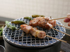 美濃焼の炭焼き水コンロを使用して屋外で肉をグリルしている様子