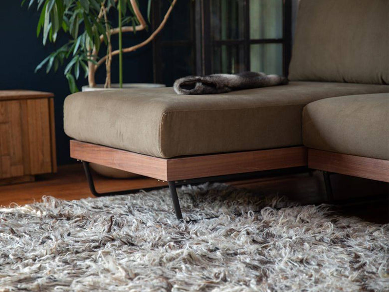 木製フローリングのリビングルームに配置されたウォルナットフレームのウェルメカウチソファ