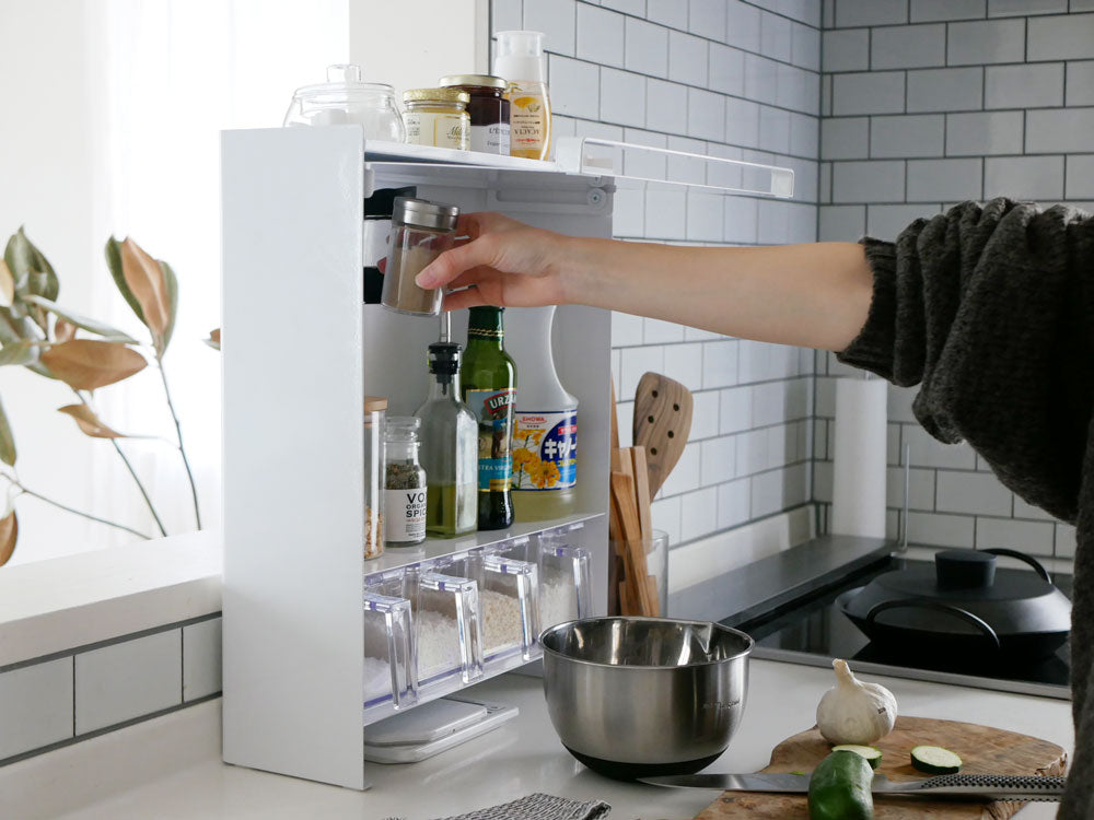 キッチンカウンター上に置かれた「tower/タワー」の調味料ラック。スチール製の棚にガラスボトルやワインボトル、テーブルウェアが整然と収納されており、便利な収納スペースを提供しています。