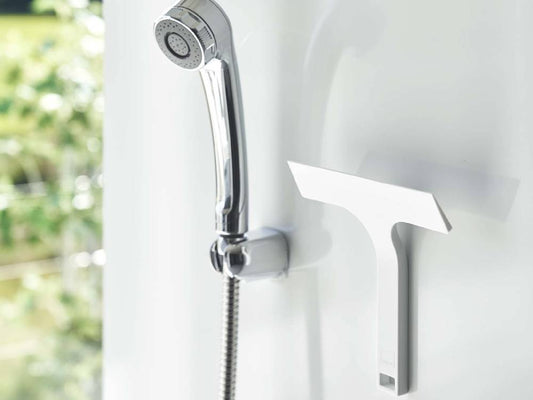 タワー マグネット水切りワイパー Sが浴室のスチール壁に取り付けられ、シリコーン製ハンドルが蛇口の近くに配置されている様子