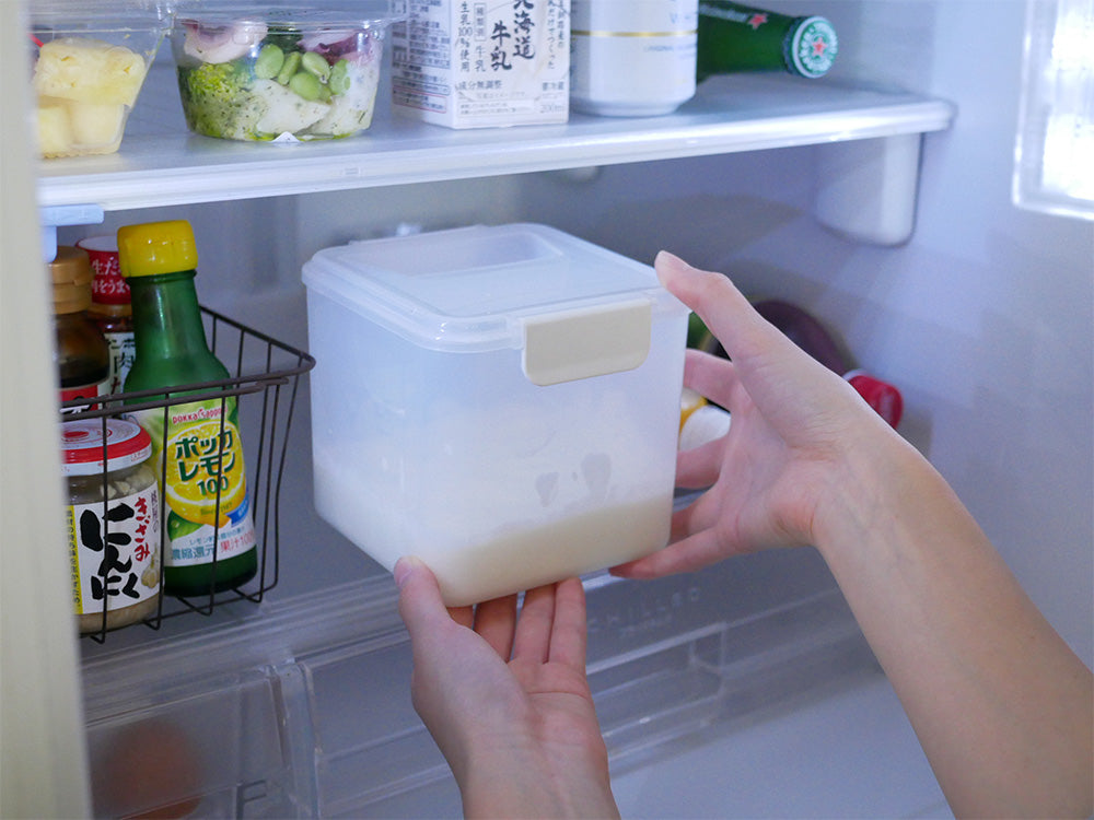 ビタントニオの発酵メーカーがキッチンカウンターに置かれ、周囲に食品保存用のプラスチック容器や新鮮な食材が配置されている様子