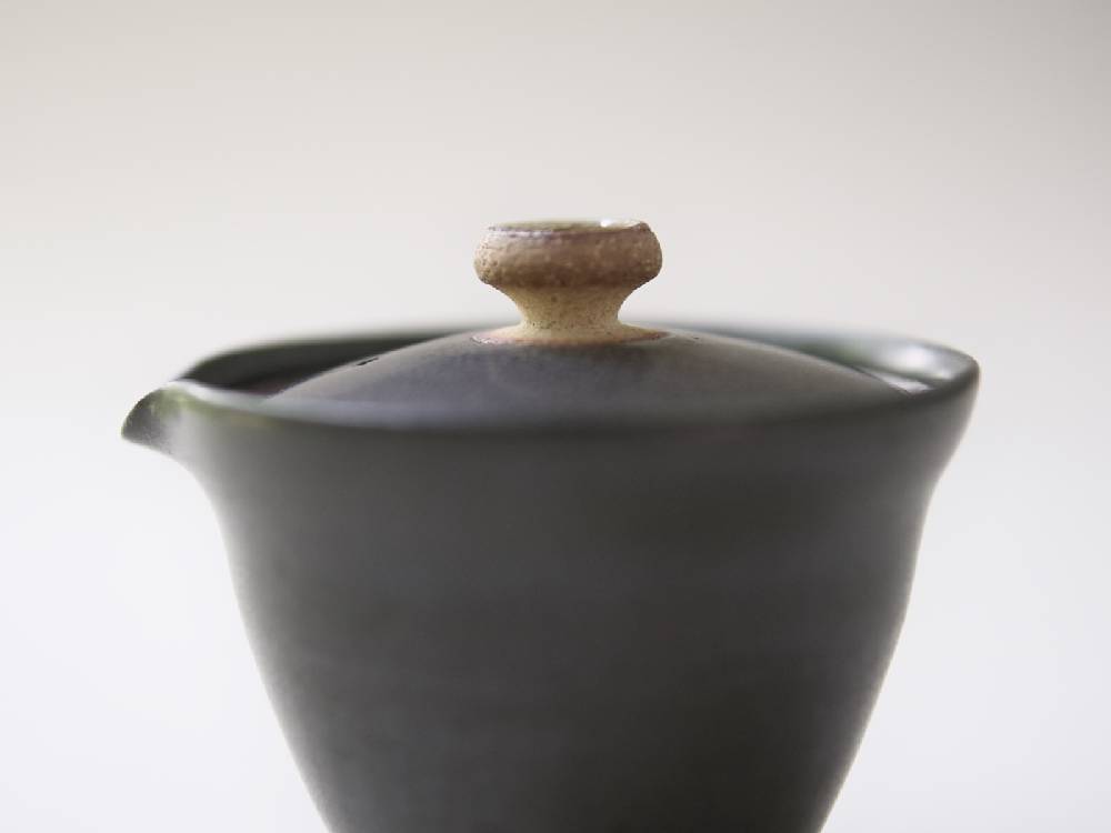 白と黒の陶器製急須と小茶碗のセット、蓋付き。
