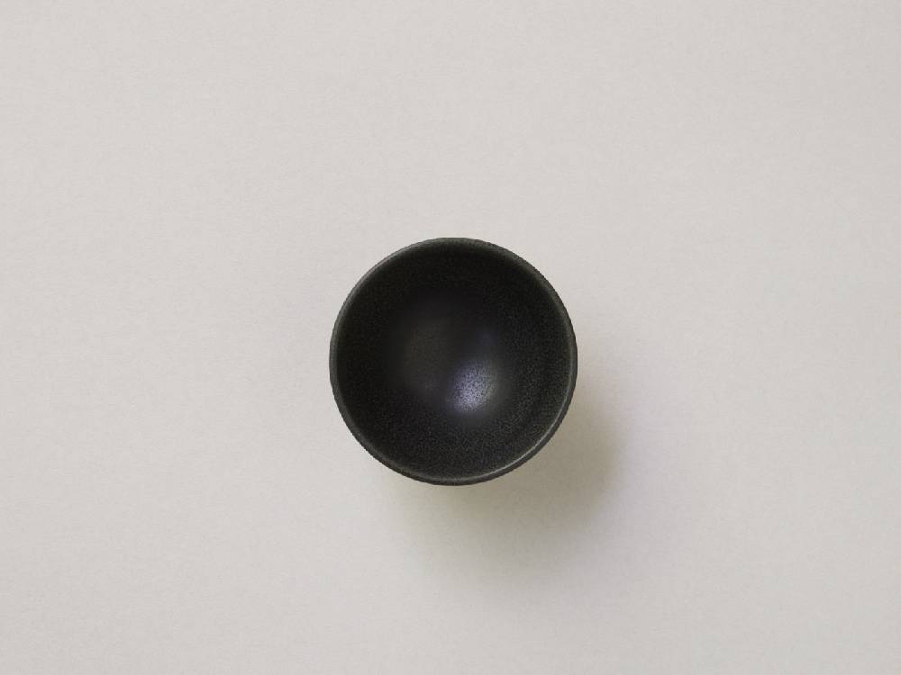 シルバーのボタンが付いた白黒陶器の急須と小茶碗がバランスよく配置された静物写真