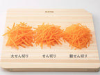 カッティングボードの上でセレクト100のせん切り器を使用し、野菜やチーズを切っている様子