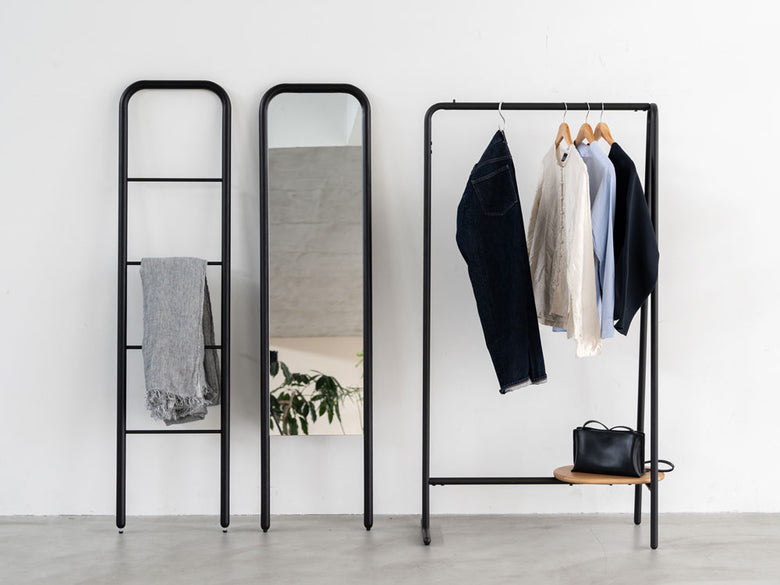 NOWHERE LIKE HOMEのスタンドミラーに付属するメタル製ラダーハンガーに衣服ハンガーとバッグが掛けられている様子